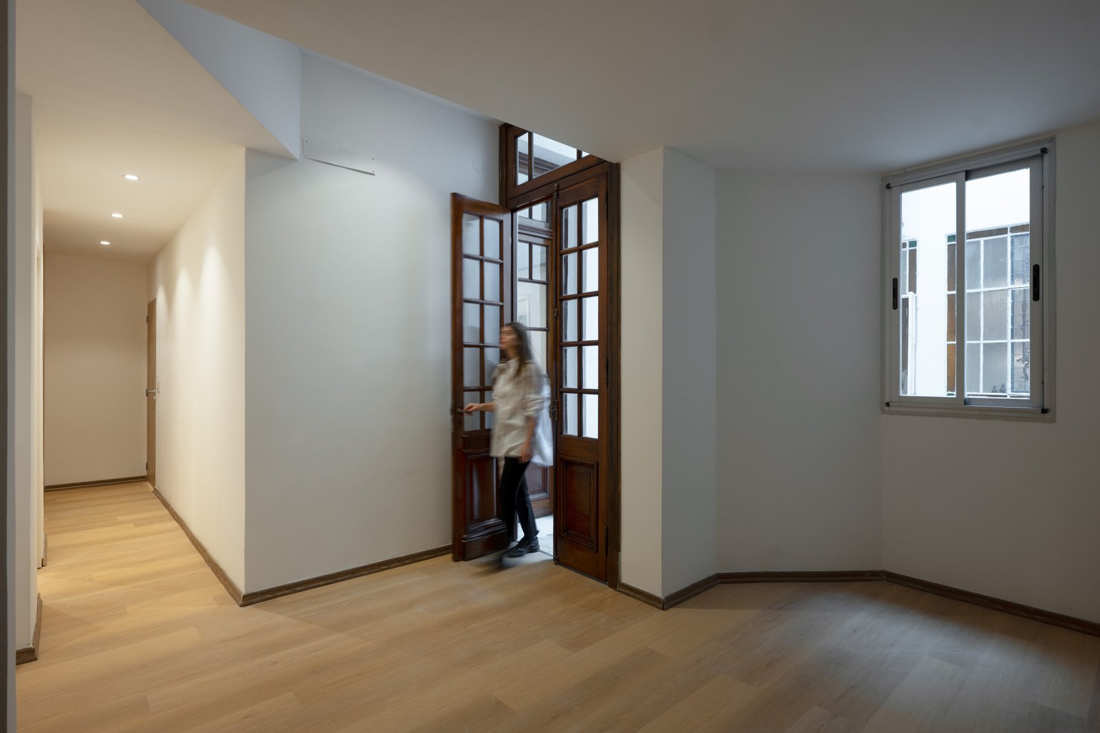 Pasillo curvo moderno con detalles en madera y puerta de vidrio — proyecto Casa Gainza, por Estudio Plats, en Caballito